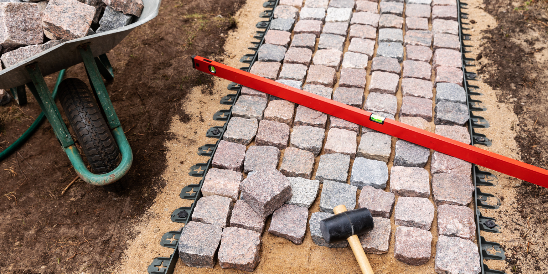 A brick walkway being laid out with a red tape