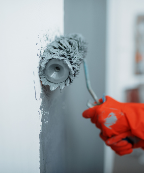 A person using a paint roller to paint a wall